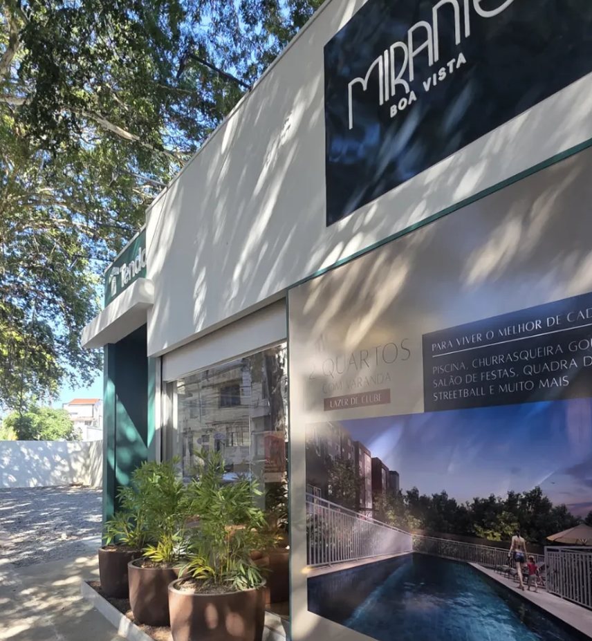 Fachada lateral do stand Tenda São Cristóvão, com a marca do empreendimento e painel da área de lazer voltados para a rua